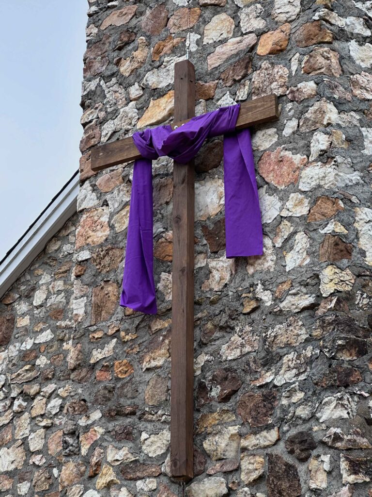 Cross with a purple shroud on the rock wall of Bluemont Presbyterian Church