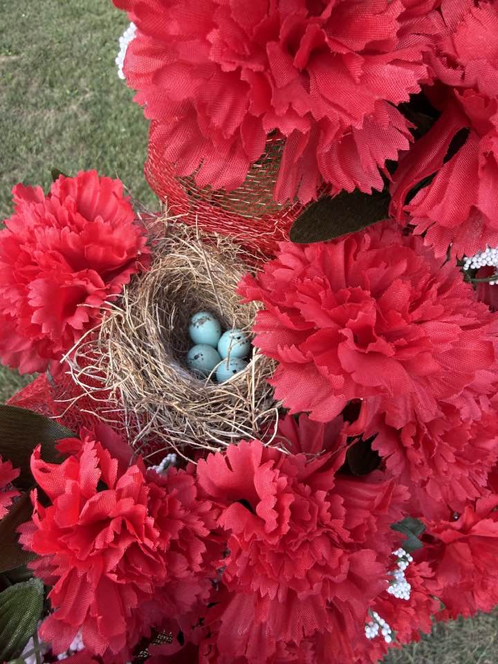Bird nest in arms of a cross decorated for Pentecost 