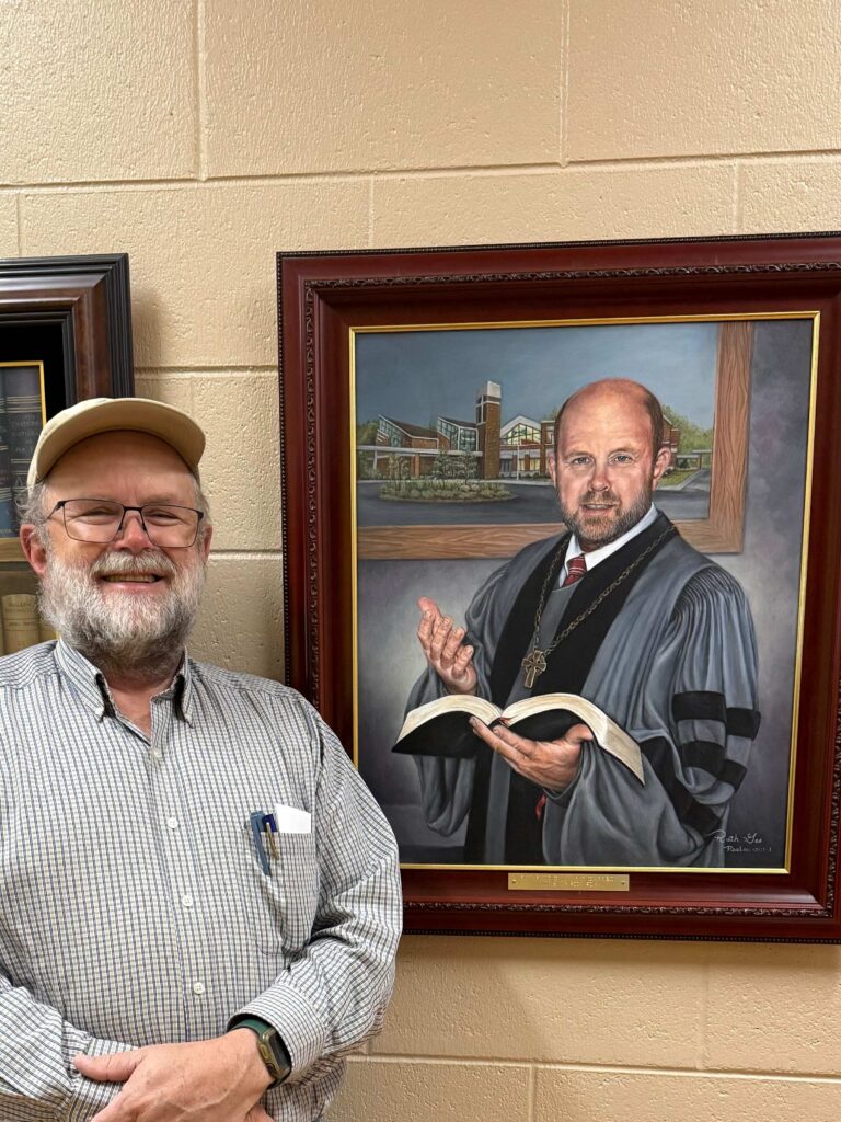 author standing by his portrait 